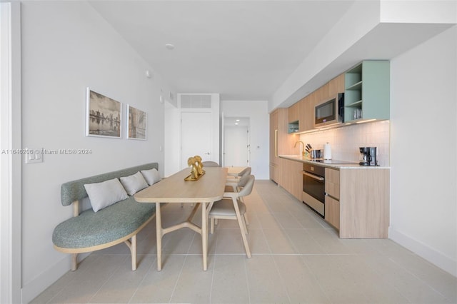 kitchen featuring light tile patterned floors, stainless steel appliances, decorative backsplash, and light brown cabinets