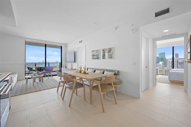 tiled dining area featuring a wealth of natural light and a wall of windows