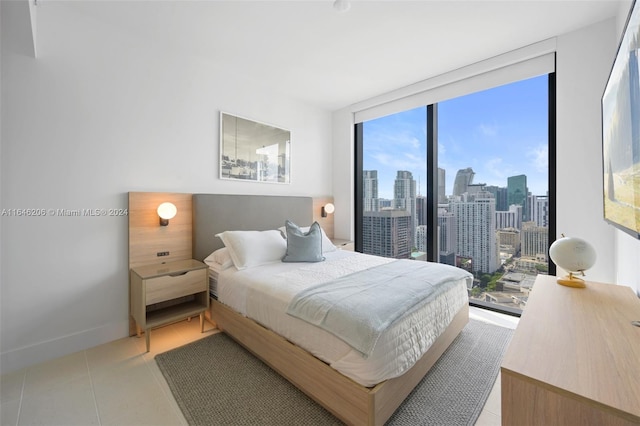 bedroom with multiple windows, expansive windows, access to exterior, and light tile patterned floors