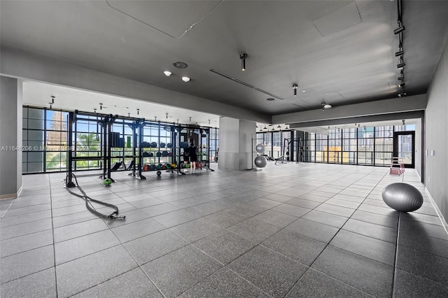 exercise room featuring tile patterned floors, rail lighting, and a healthy amount of sunlight