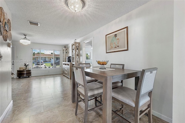 dining room featuring light tile patterned flooring, a notable chandelier, and a textured ceiling