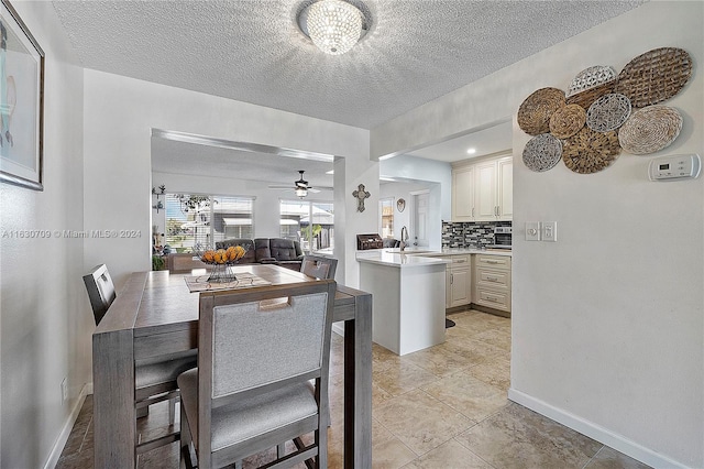 dining area with ceiling fan, sink, a textured ceiling, and light tile patterned floors