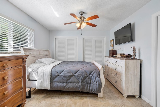 tiled bedroom with a textured ceiling, ceiling fan, and multiple closets