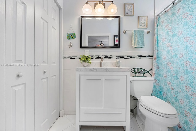 bathroom with tile patterned flooring, toilet, vanity, and tile walls