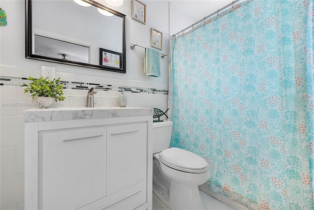 bathroom featuring tile patterned flooring, tile walls, toilet, and vanity