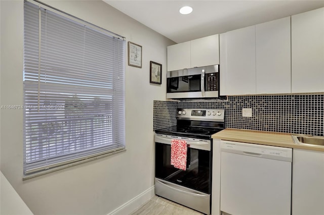 kitchen featuring decorative backsplash, white cabinetry, and appliances with stainless steel finishes