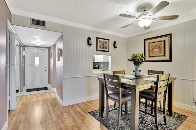 dining room with a textured ceiling, ceiling fan, and light wood-type flooring