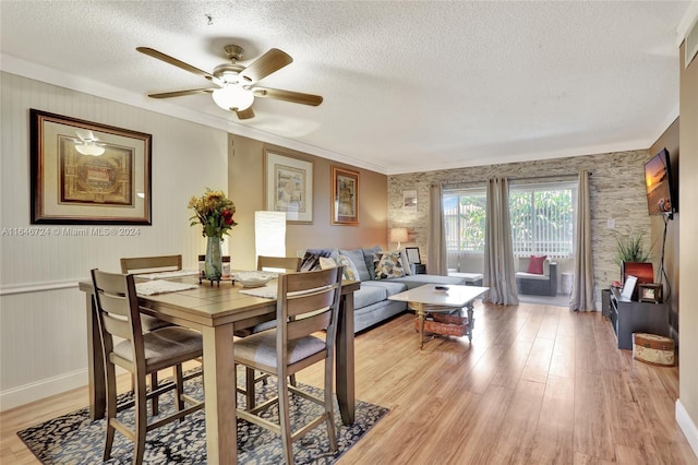 dining room featuring ceiling fan, light wood-type flooring, a textured ceiling, and crown molding