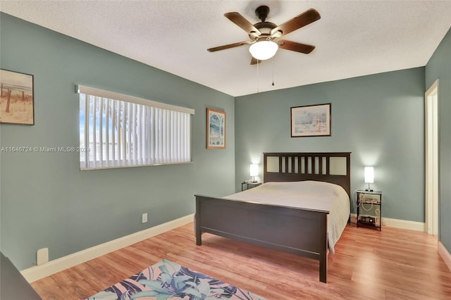 bedroom with a textured ceiling, ceiling fan, and light wood-type flooring