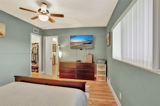 bedroom with ceiling fan, light wood-type flooring, a spacious closet, and a closet