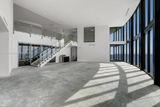 unfurnished living room featuring stairway and concrete floors