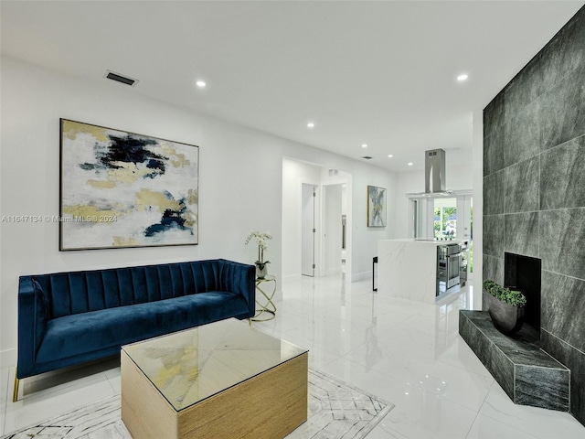 living area with marble finish floor, a tile fireplace, visible vents, and recessed lighting