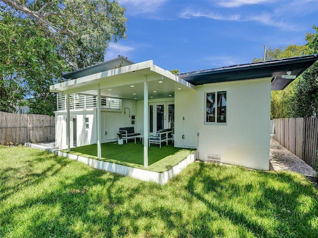 back of property with french doors, a fenced backyard, a yard, and stucco siding