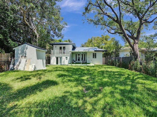 rear view of house featuring an outbuilding, metal roof, fence, a lawn, and a standing seam roof