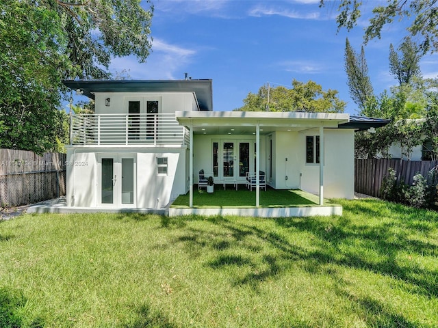 rear view of property with french doors, a fenced backyard, a lawn, and stucco siding