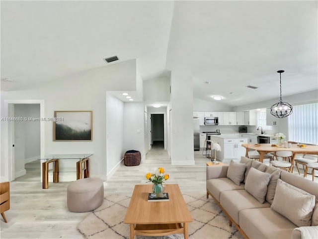 living room featuring light hardwood / wood-style floors, an inviting chandelier, and lofted ceiling