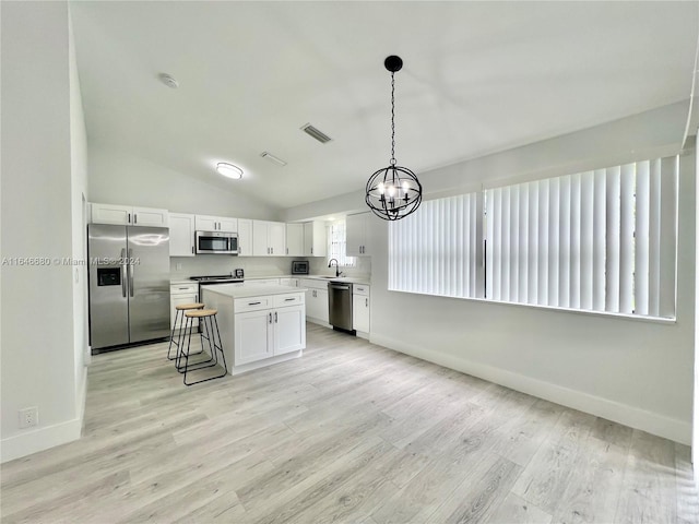 kitchen featuring appliances with stainless steel finishes, a breakfast bar, white cabinets, a kitchen island, and lofted ceiling