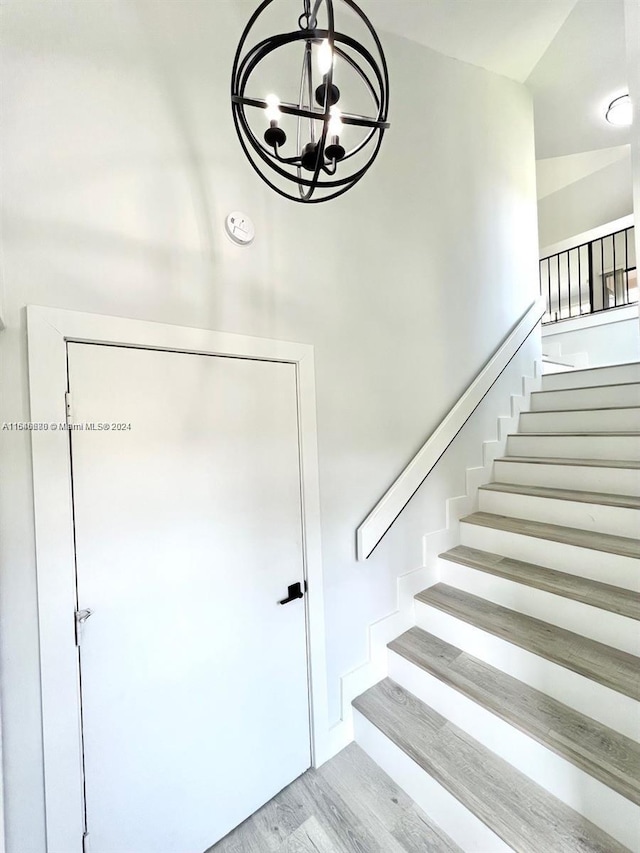 stairway with hardwood / wood-style floors and an inviting chandelier