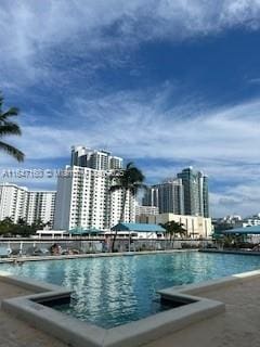 view of pool with a view of city and a water view