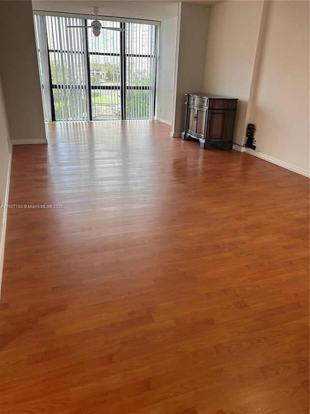 unfurnished living room featuring wood finished floors and baseboards