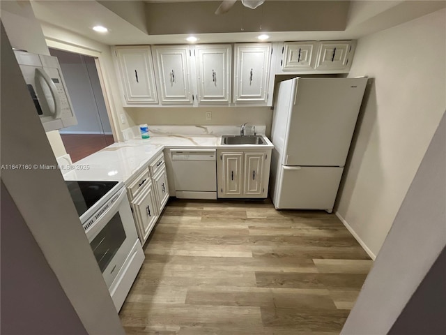 kitchen featuring white appliances, light stone counters, a sink, white cabinets, and light wood-type flooring