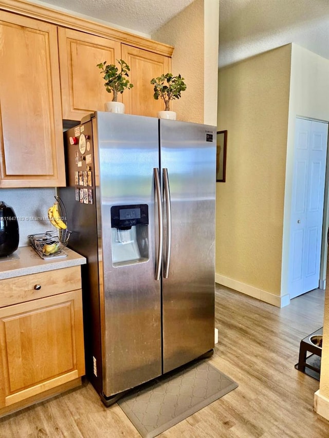 kitchen with appliances with stainless steel finishes, light hardwood / wood-style flooring, a textured ceiling, and light brown cabinets