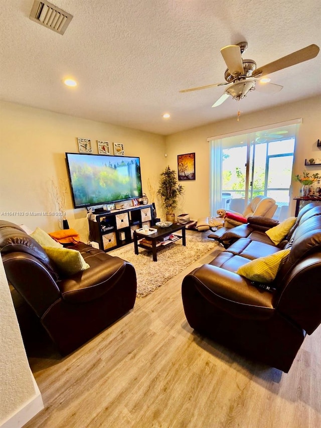 living room with ceiling fan, a textured ceiling, and hardwood / wood-style floors