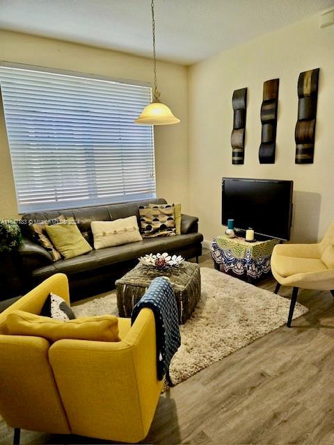 living room with a textured ceiling, light hardwood / wood-style floors, and ceiling fan