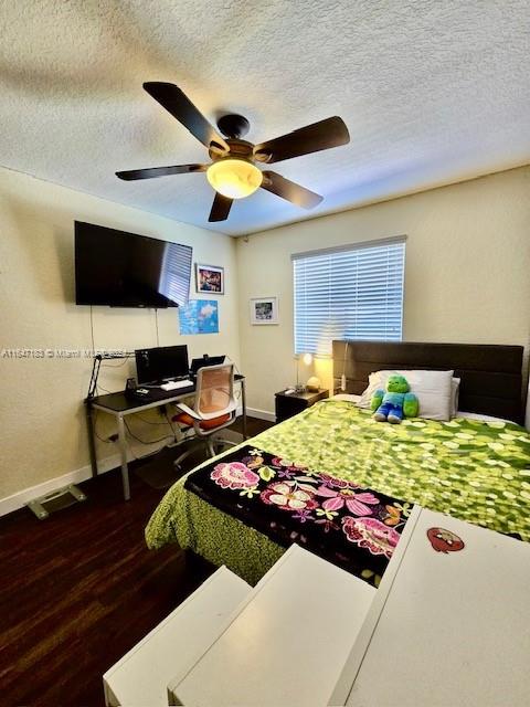 bedroom with a closet, a textured ceiling, dark wood-type flooring, and ceiling fan