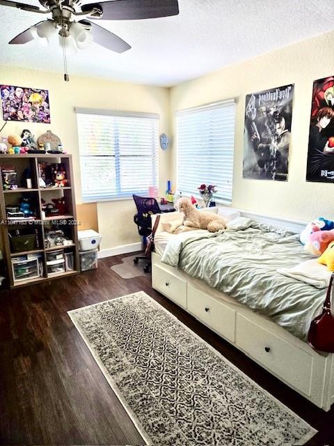 bedroom with dark wood-type flooring, a textured ceiling, and ceiling fan