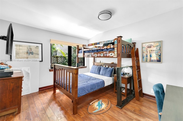 bedroom with vaulted ceiling and hardwood / wood-style flooring