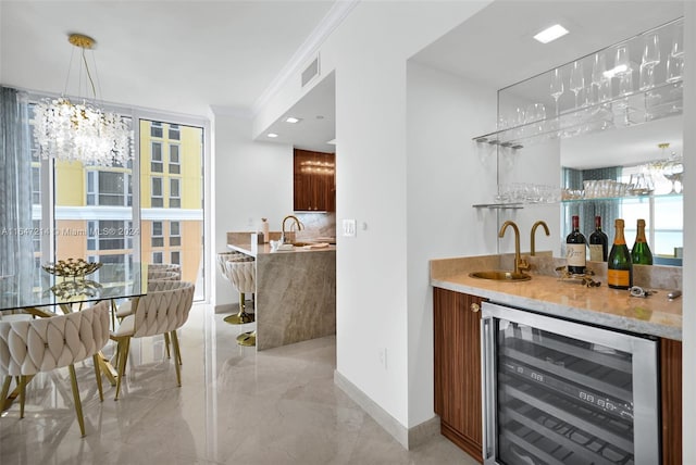 bar featuring wine cooler, sink, a notable chandelier, decorative light fixtures, and crown molding