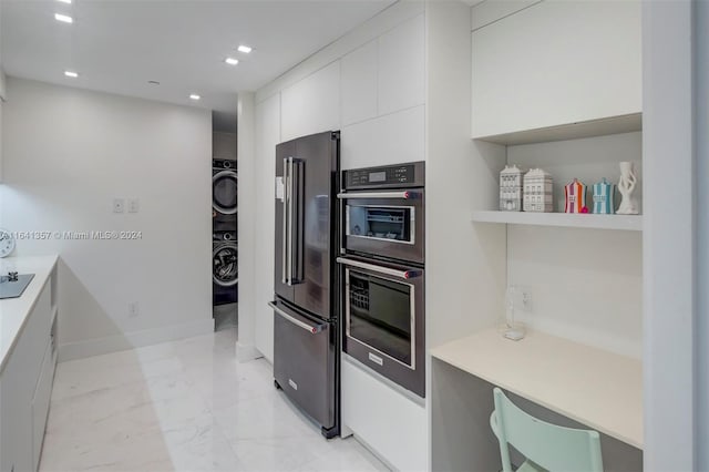 kitchen with light tile patterned floors, stacked washer and dryer, appliances with stainless steel finishes, tasteful backsplash, and white cabinetry