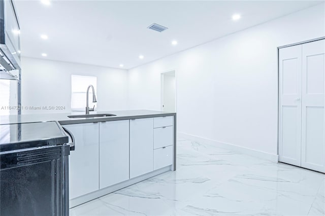 kitchen featuring range with electric stovetop, sink, and white cabinets