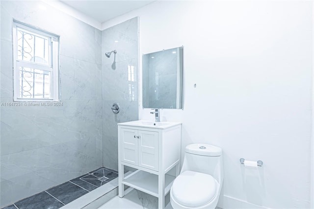 bathroom with tiled shower, vanity, and toilet