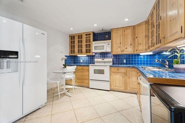 kitchen featuring tile countertops, sink, decorative backsplash, light tile patterned floors, and white appliances