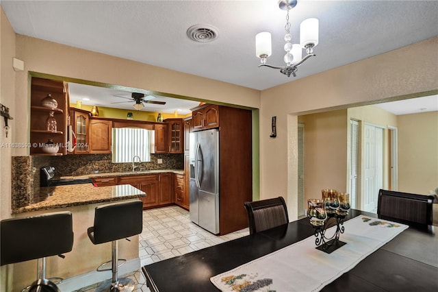 kitchen featuring decorative backsplash, stainless steel appliances, sink, decorative light fixtures, and ceiling fan with notable chandelier