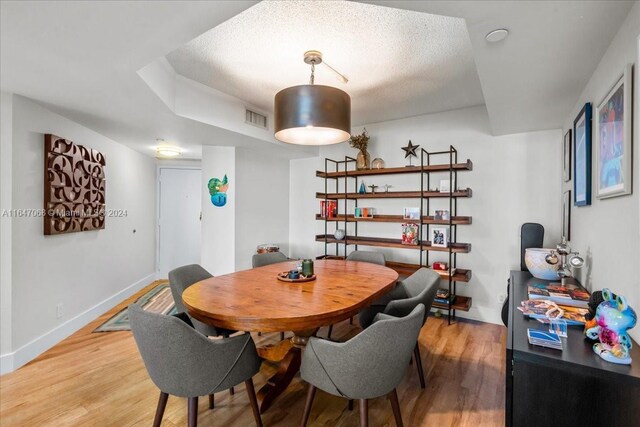 dining space featuring wood-type flooring and a textured ceiling