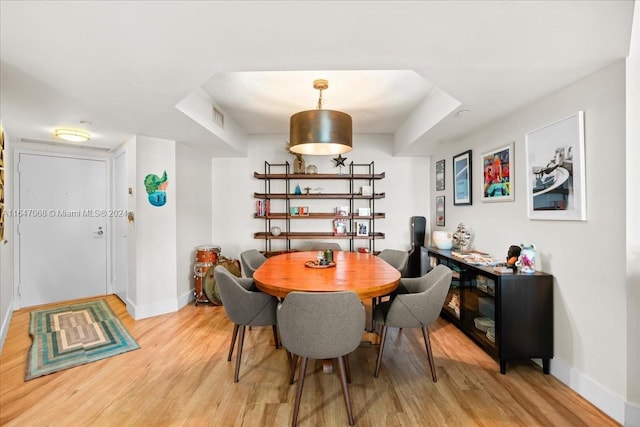 dining area featuring light wood finished floors, visible vents, and baseboards