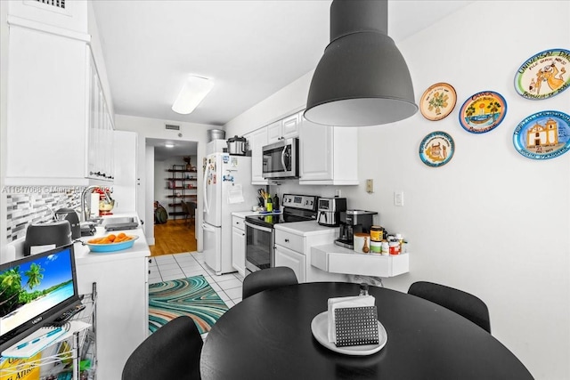 kitchen with light tile patterned floors, white cabinets, appliances with stainless steel finishes, light countertops, and a sink