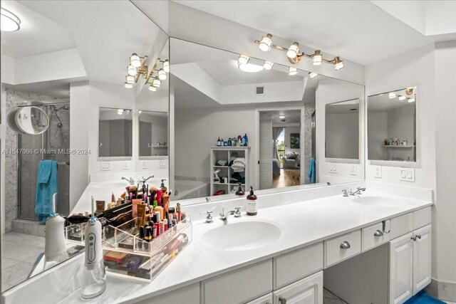 full bathroom with visible vents, a sink, a shower stall, and double vanity