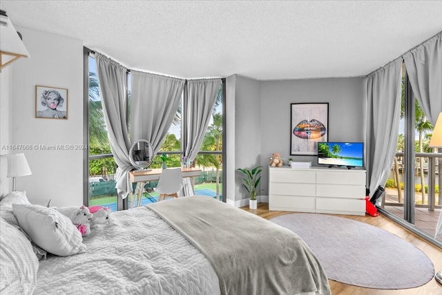 bedroom with a textured ceiling, light hardwood / wood-style floors, and access to outside