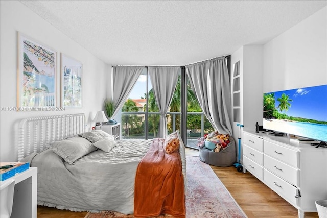 bedroom with light wood-style floors, access to outside, and a textured ceiling