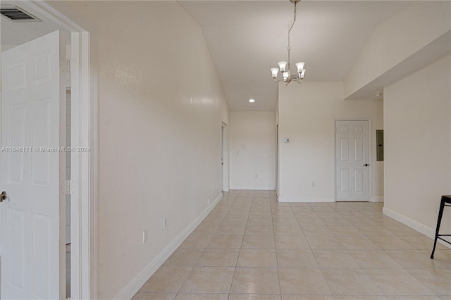 empty room featuring a notable chandelier, light tile patterned floors, and lofted ceiling