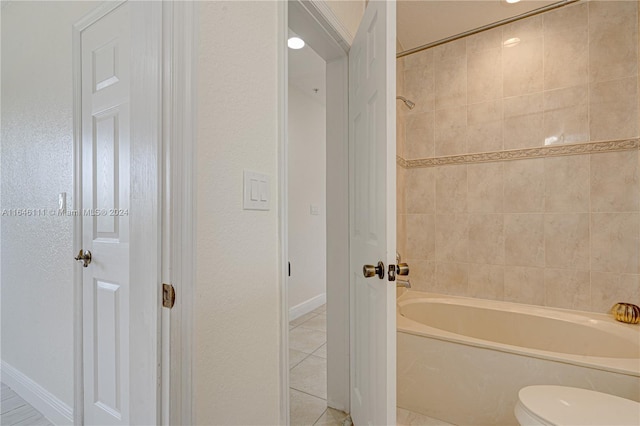 bathroom with toilet, tiled shower / bath combo, and tile patterned floors