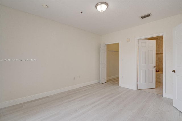 unfurnished bedroom featuring a spacious closet, light hardwood / wood-style flooring, and a closet