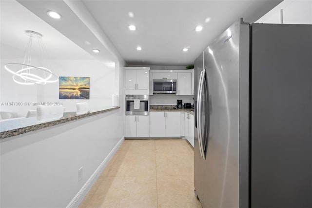 kitchen featuring light tile patterned flooring, decorative light fixtures, appliances with stainless steel finishes, light stone counters, and white cabinets