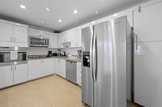 kitchen featuring stainless steel appliances, white cabinetry, stone counters, sink, and light tile patterned flooring