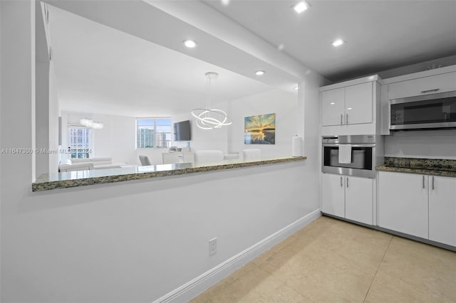 kitchen with light tile patterned floors, dark stone countertops, white cabinetry, stainless steel appliances, and pendant lighting