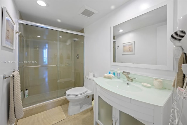 bathroom with vanity, toilet, tile patterned floors, and a shower with shower door